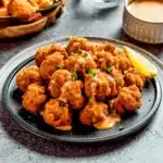 Crispy Bang Bang Chicken bites drizzled with sweet chili sauce served with a lemon wedge, ideal with basmati rice or potato sides.