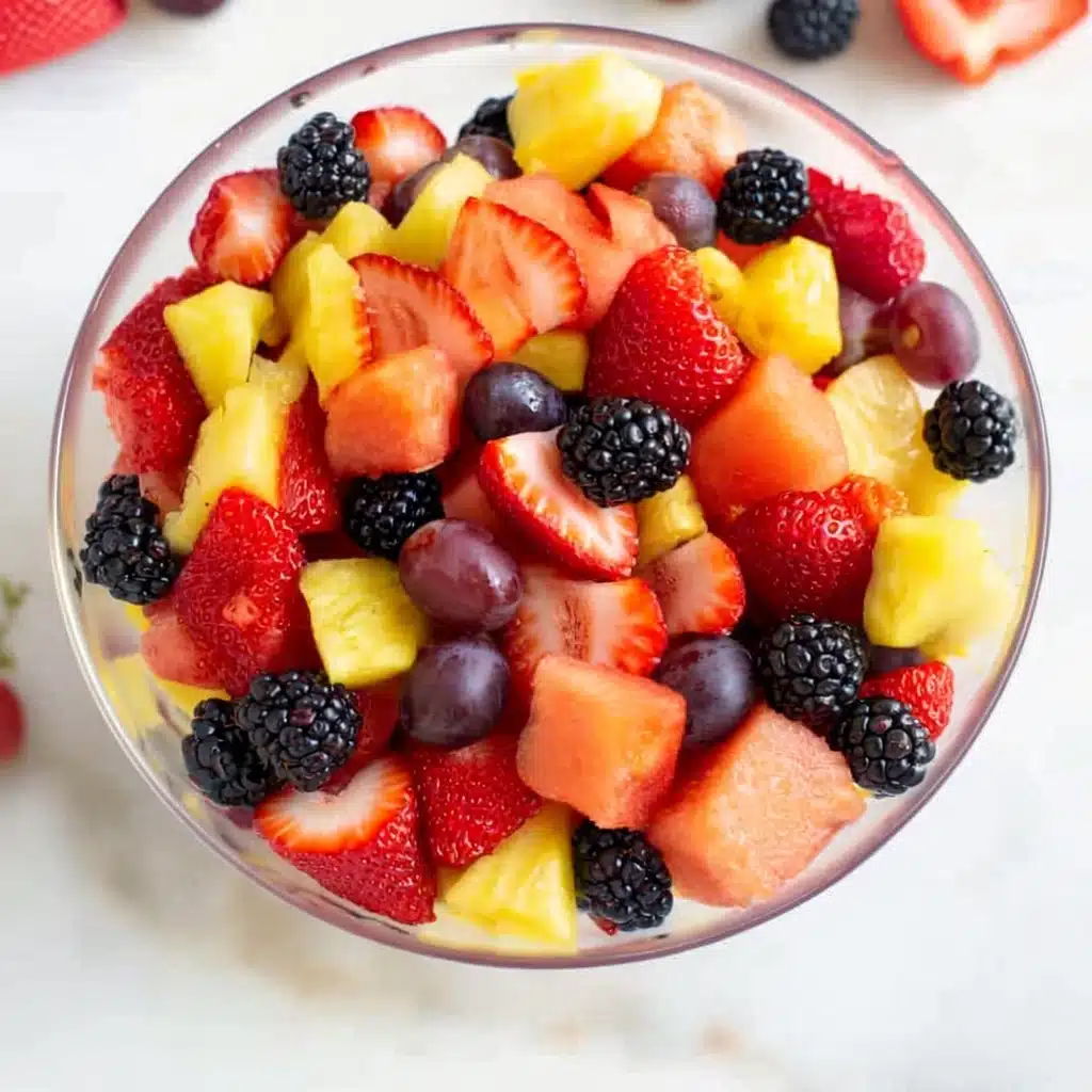 Refreshing summer fruit salad with watermelon, pineapple, strawberries, grapes, and blackberries in a glass bowl