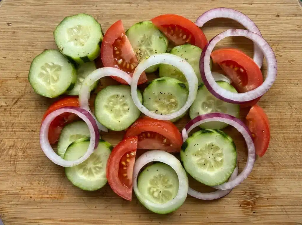 Fresh cucumbers tomatoes and onions for salad prep