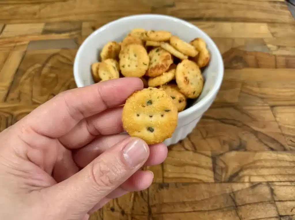 Hand holding a single Garlic Bread Ritz Bit with parsley seasoning
