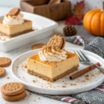 Slice of no-bake pumpkin biscoff cheesecake bar topped with whipped cream and cinnamon on white plate.