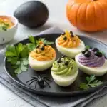 Spooky deviled eggs in four Halloween styles on a serving plate