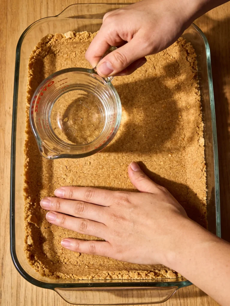 Pressing graham cracker crust into pan for icebox cheesecake
