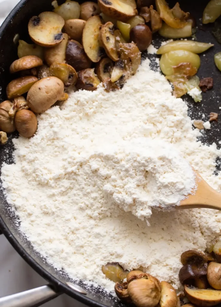 stirring flour into mushrooms to make gravy roux